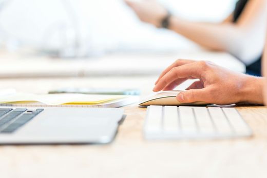 A person is typing on a computer mouse and keyboard.
