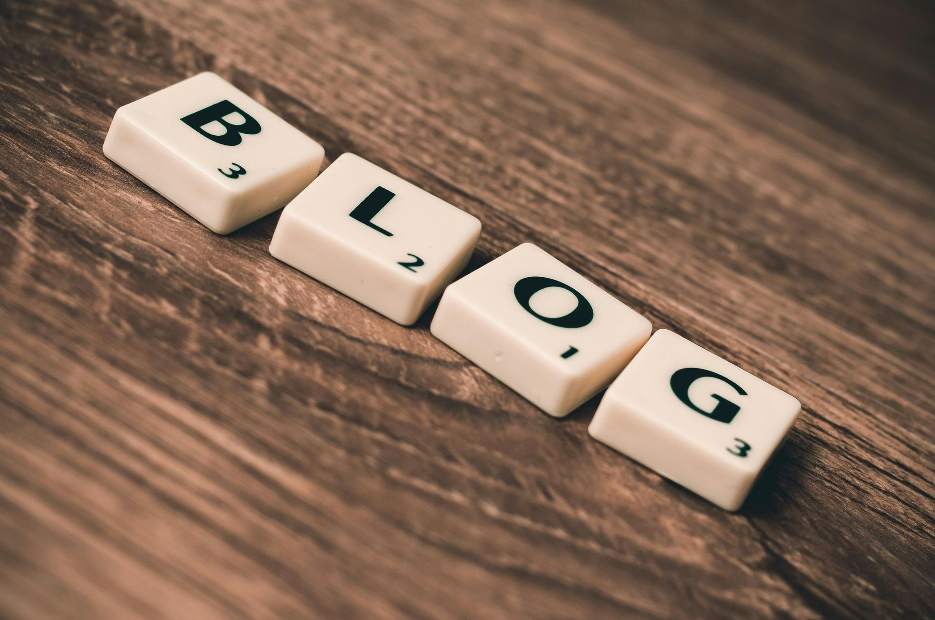 Scrabble tiles spelling out the word blog on a wooden table, a blog is a great way to give your site authority because it allows more content as well as links giving your site more power on google. Website design with Seo care