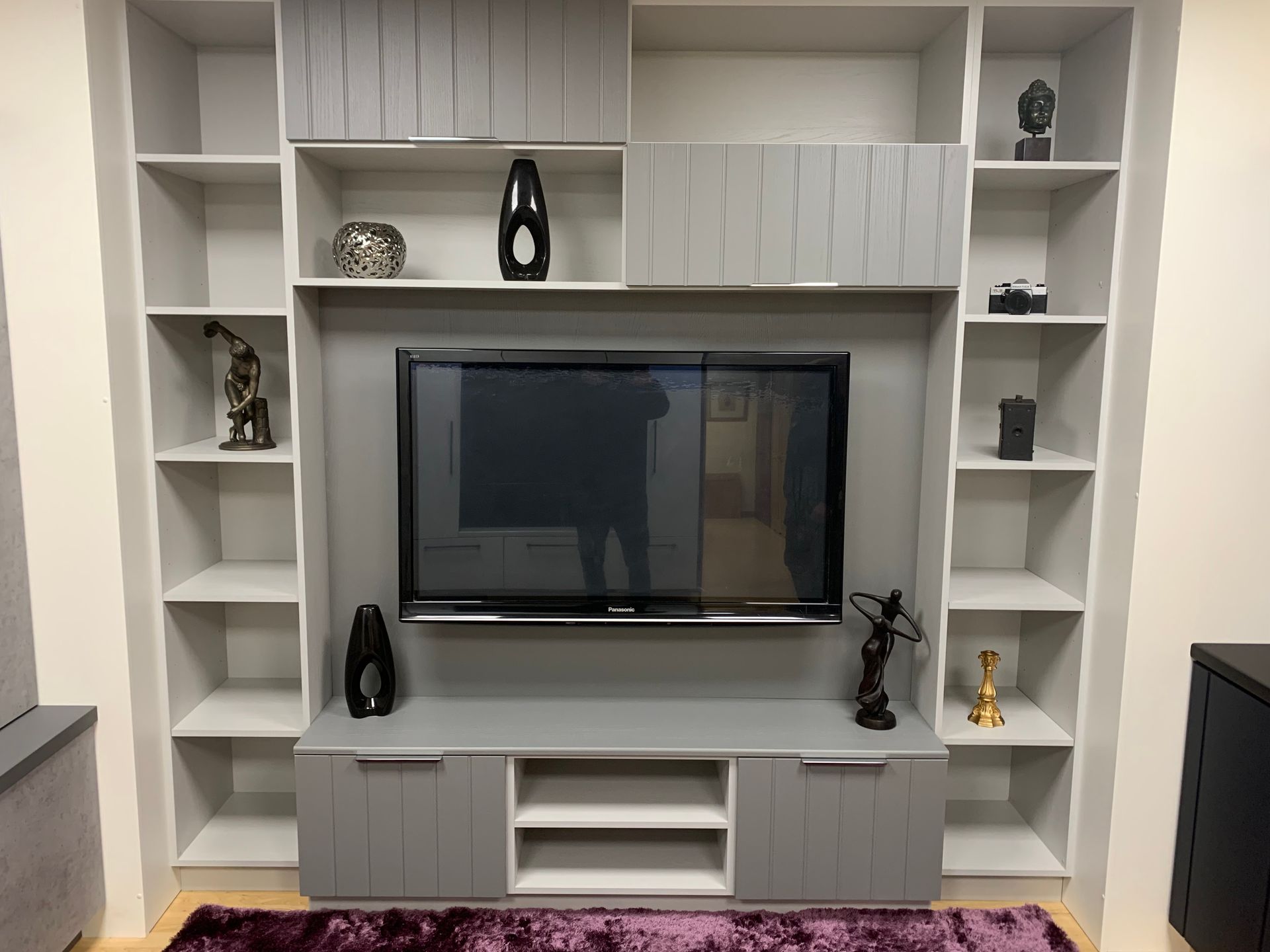a large flat screen tv is sitting on top of a shelf in a living room media wall