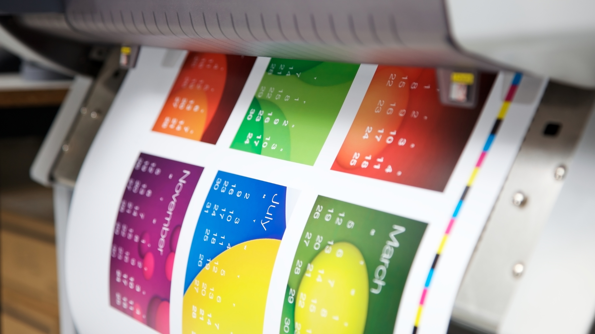 Printer printing a colorful calendar with months and gradients.