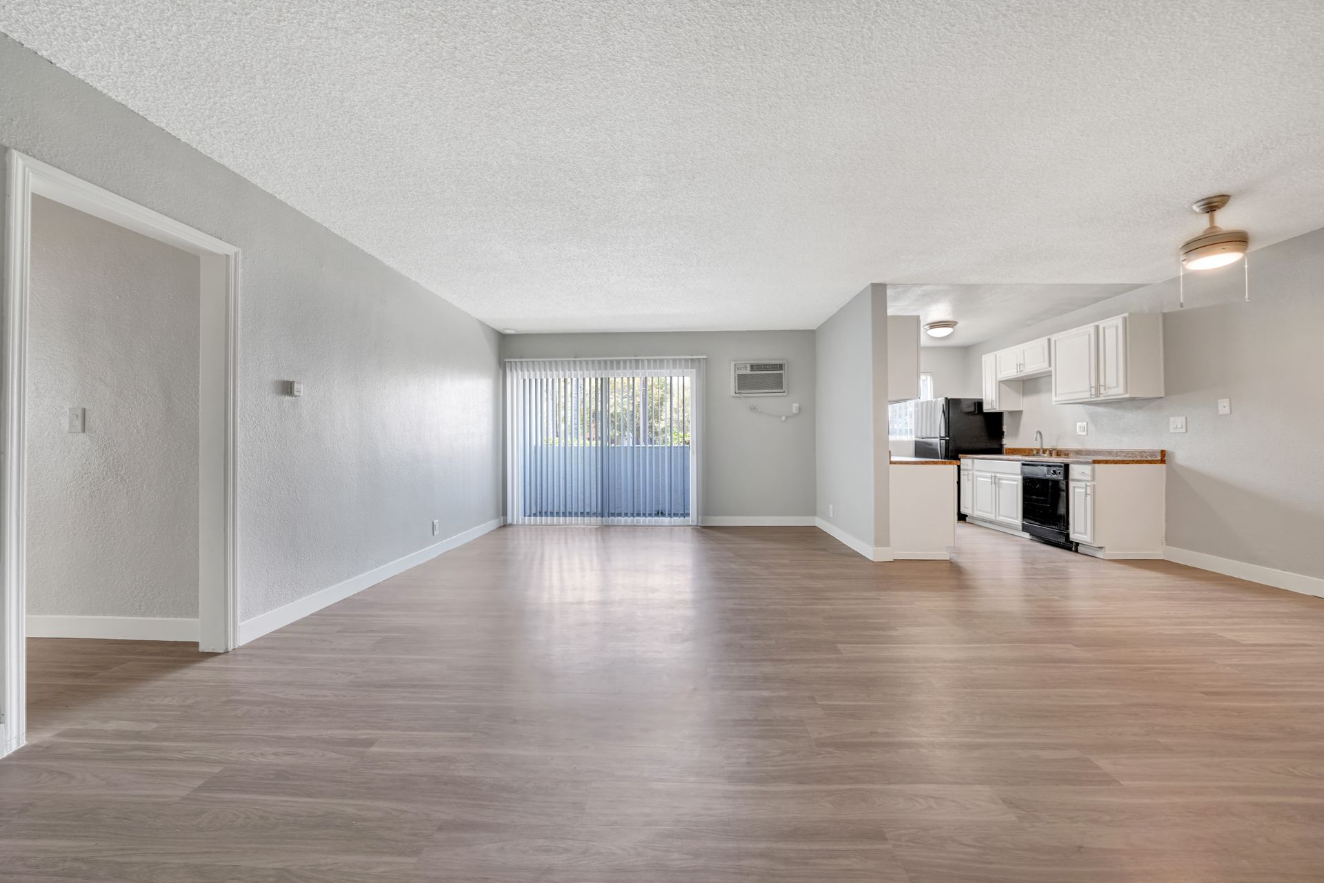 Photo of a very large living room/dining room space, showing the kitchen in the background