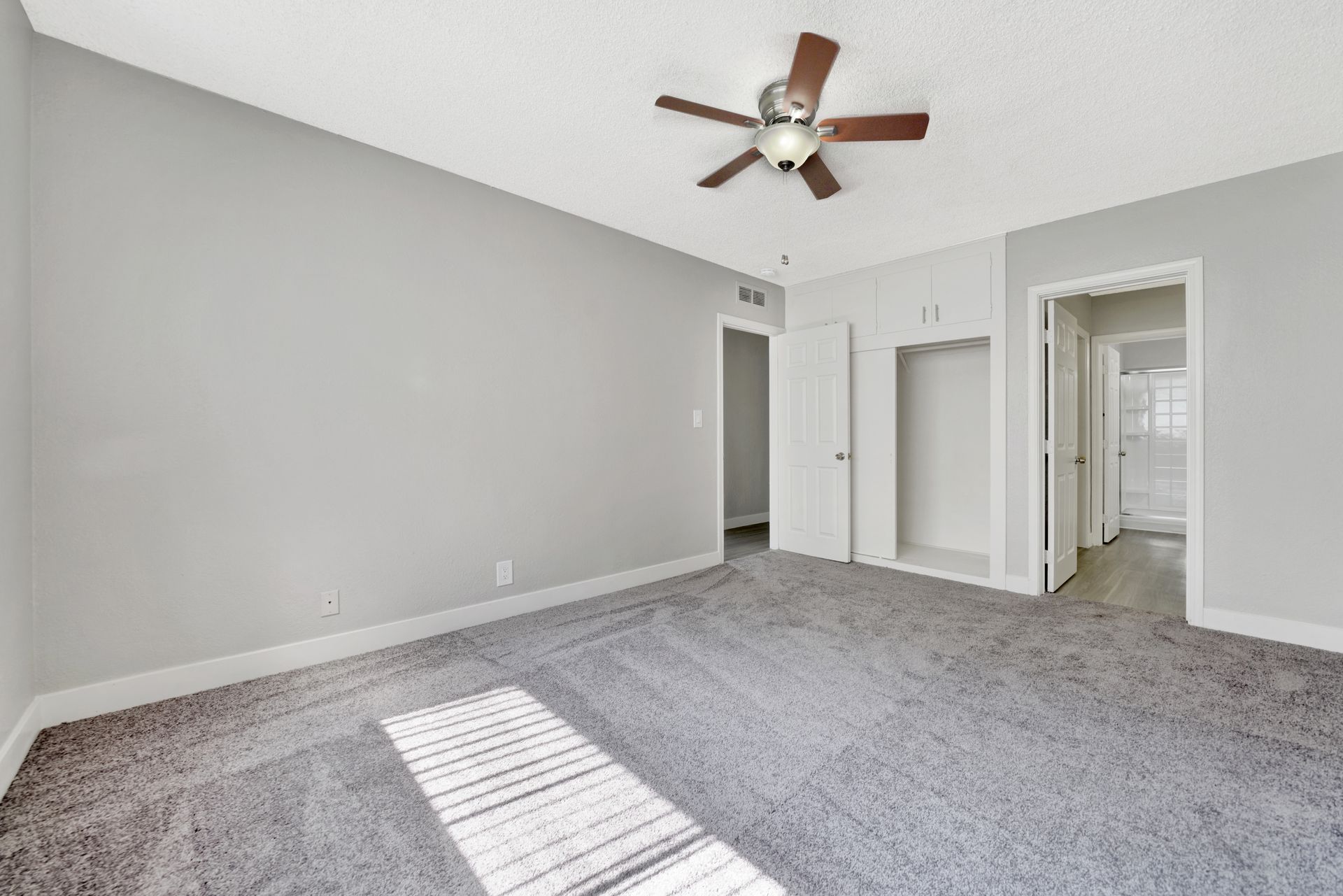 Photo of a medium-large size bedroom with a ceiling fan and a bathroom