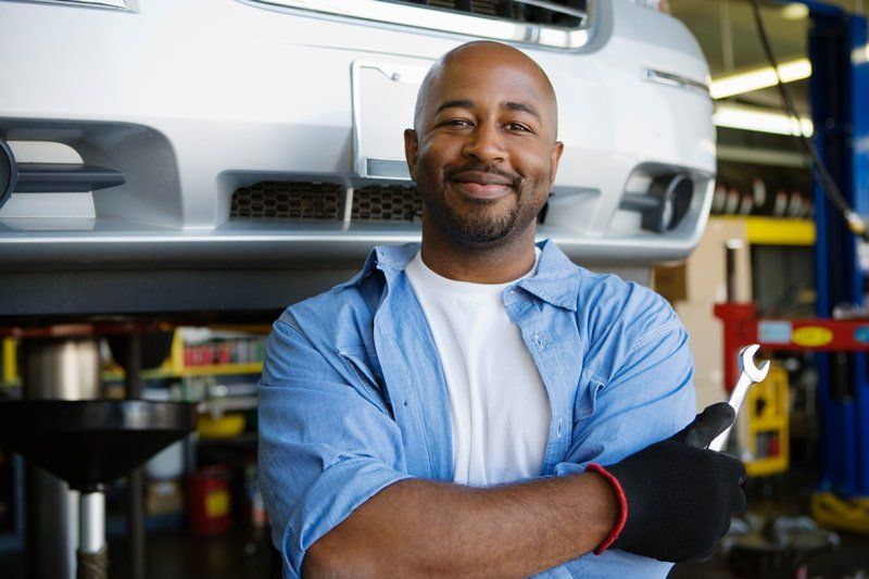 mechanic smiling next to car