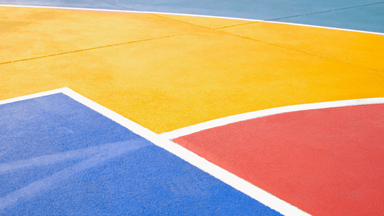 “Bright sport court surface with bold yellow, blue, and red sections and smooth painted lines during a court builder service in Henderson, NV”