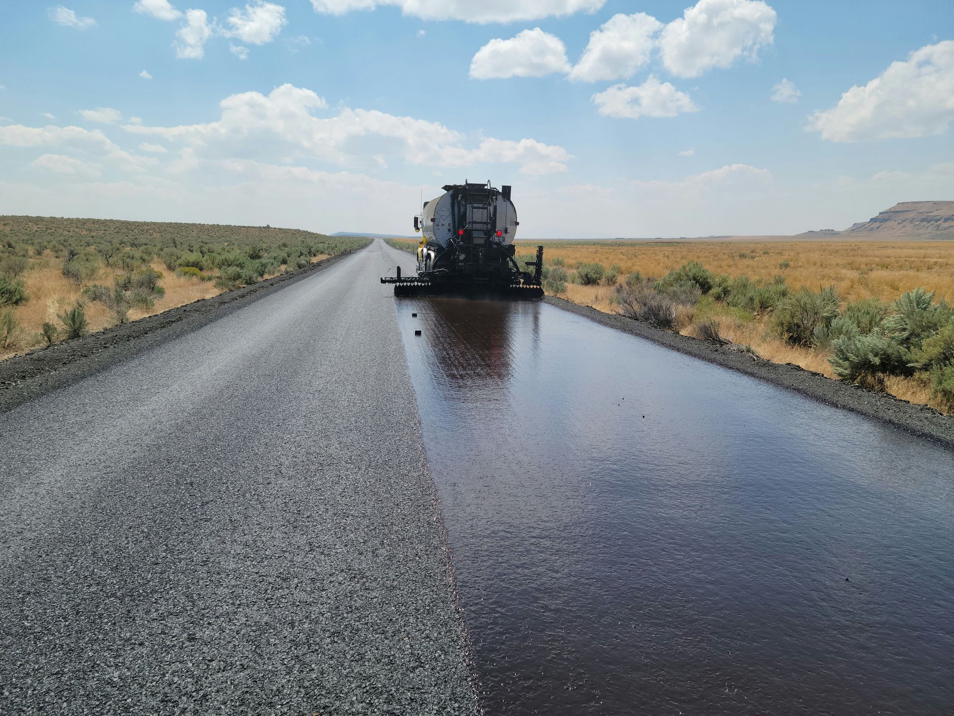 Crew sealcoating new asphalt on road after removal of old