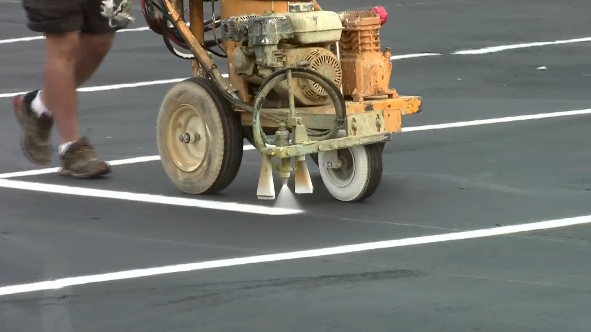Crew member striping new asphalt parking lot