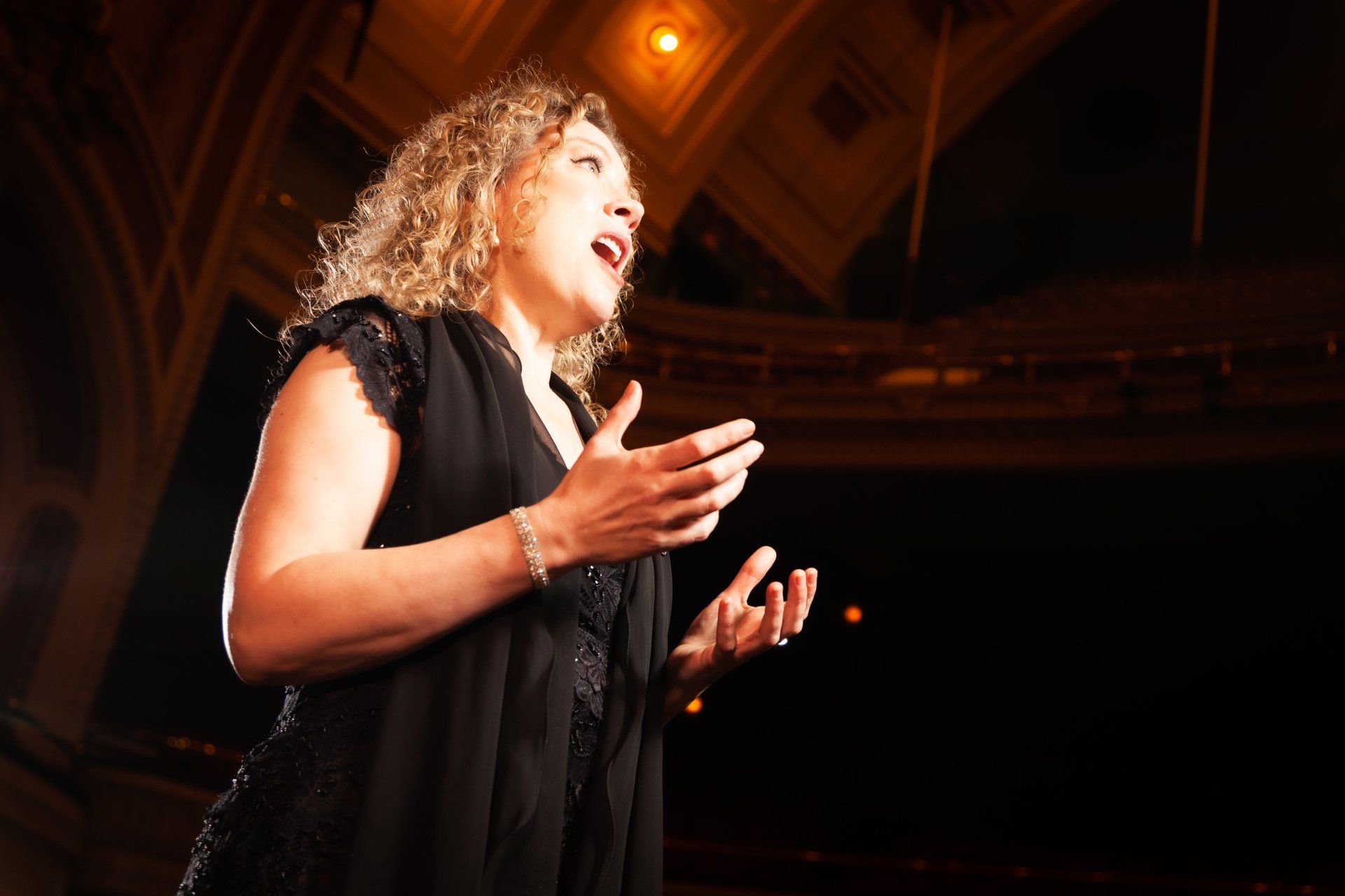 A woman in a black dress is singing into a microphone.