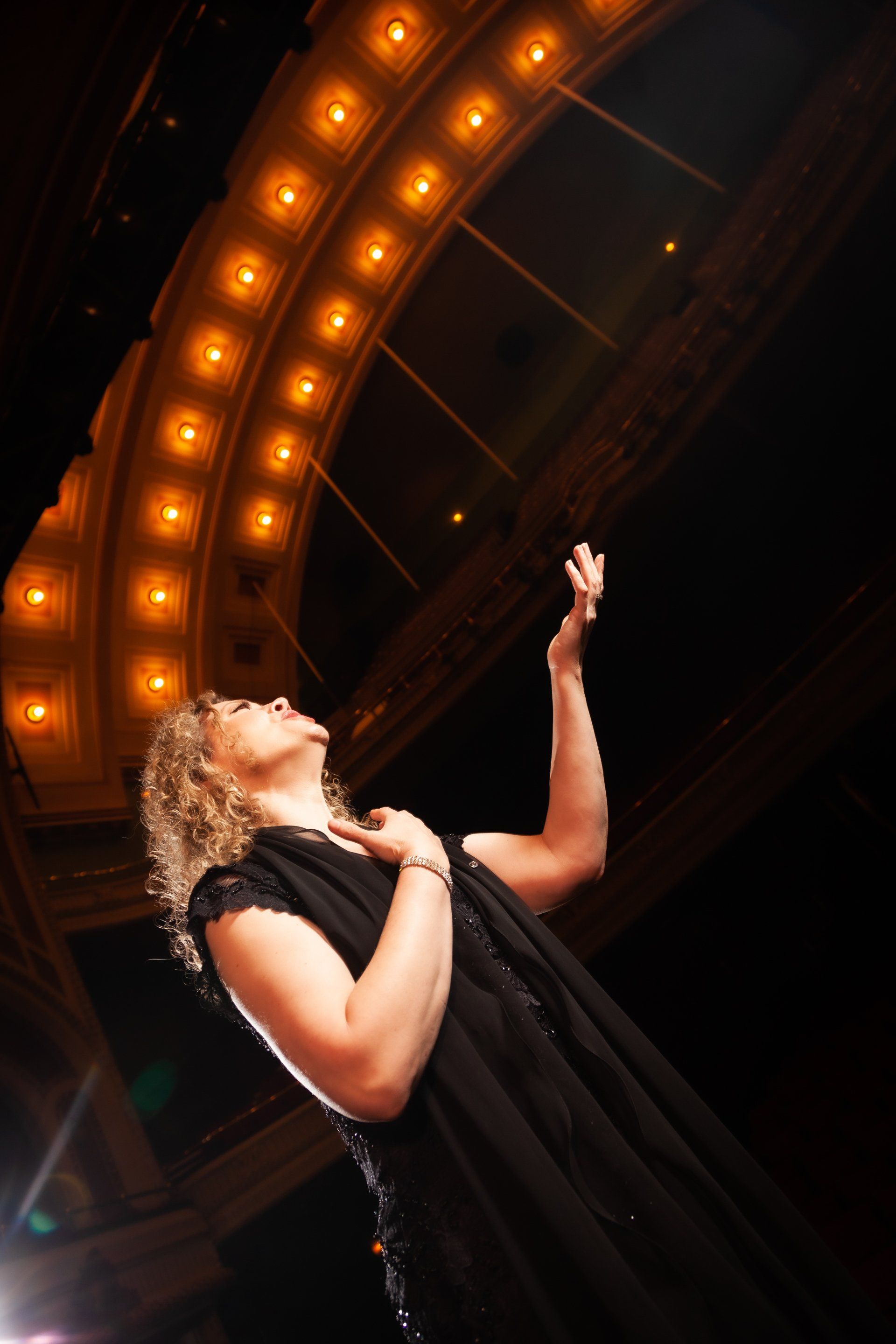 A woman in a black dress is singing into a microphone