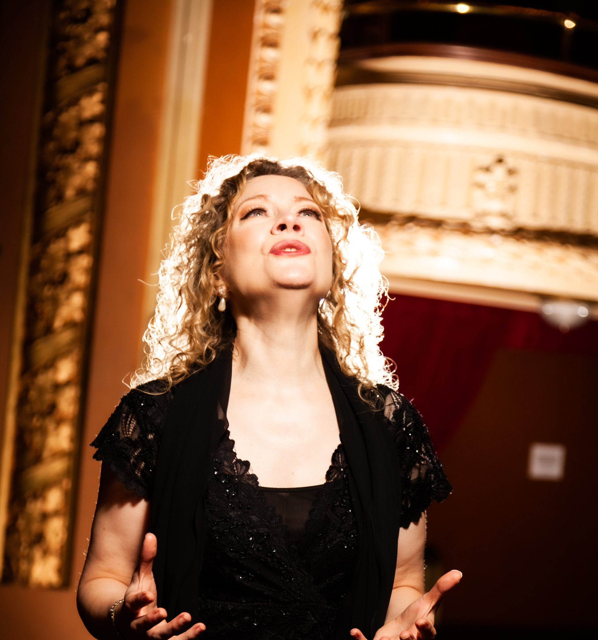 A woman in a black dress is singing into a microphone