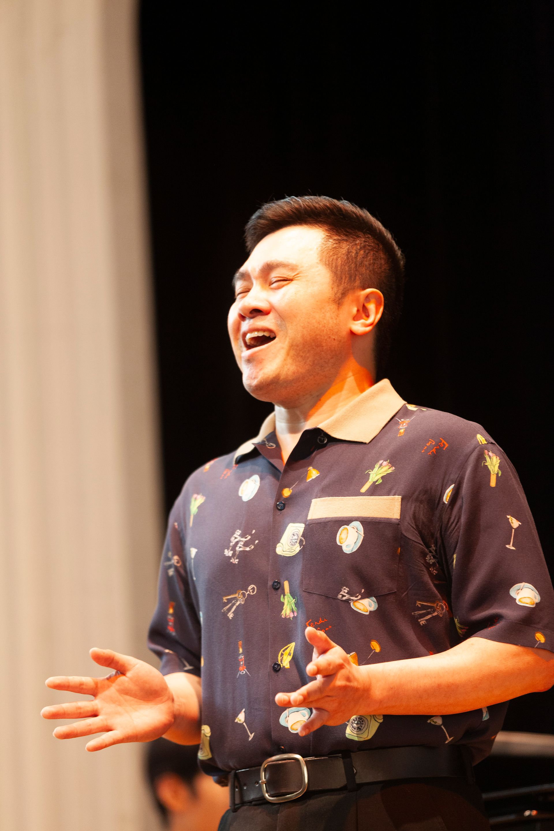 A man in a blue shirt is singing on a stage.
