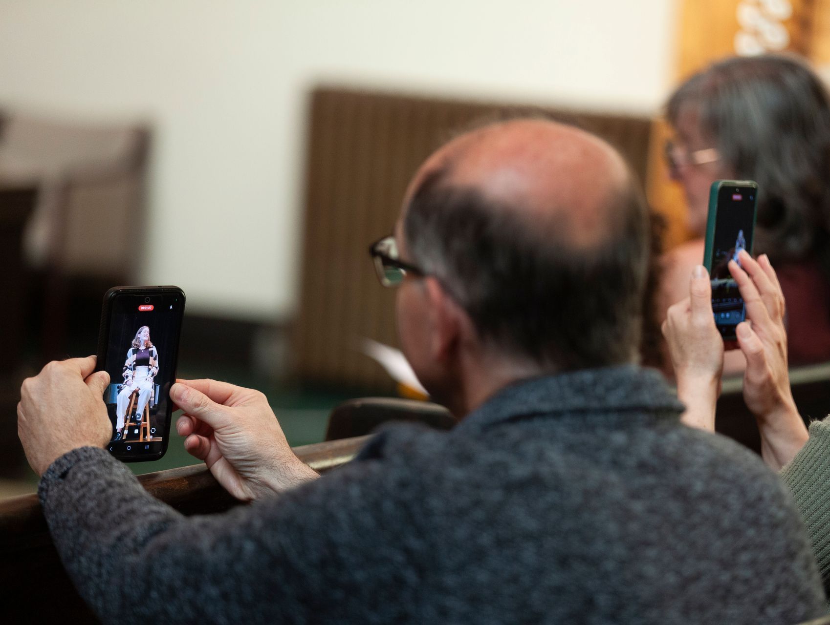 A man is taking a picture of a woman on his cell phone.