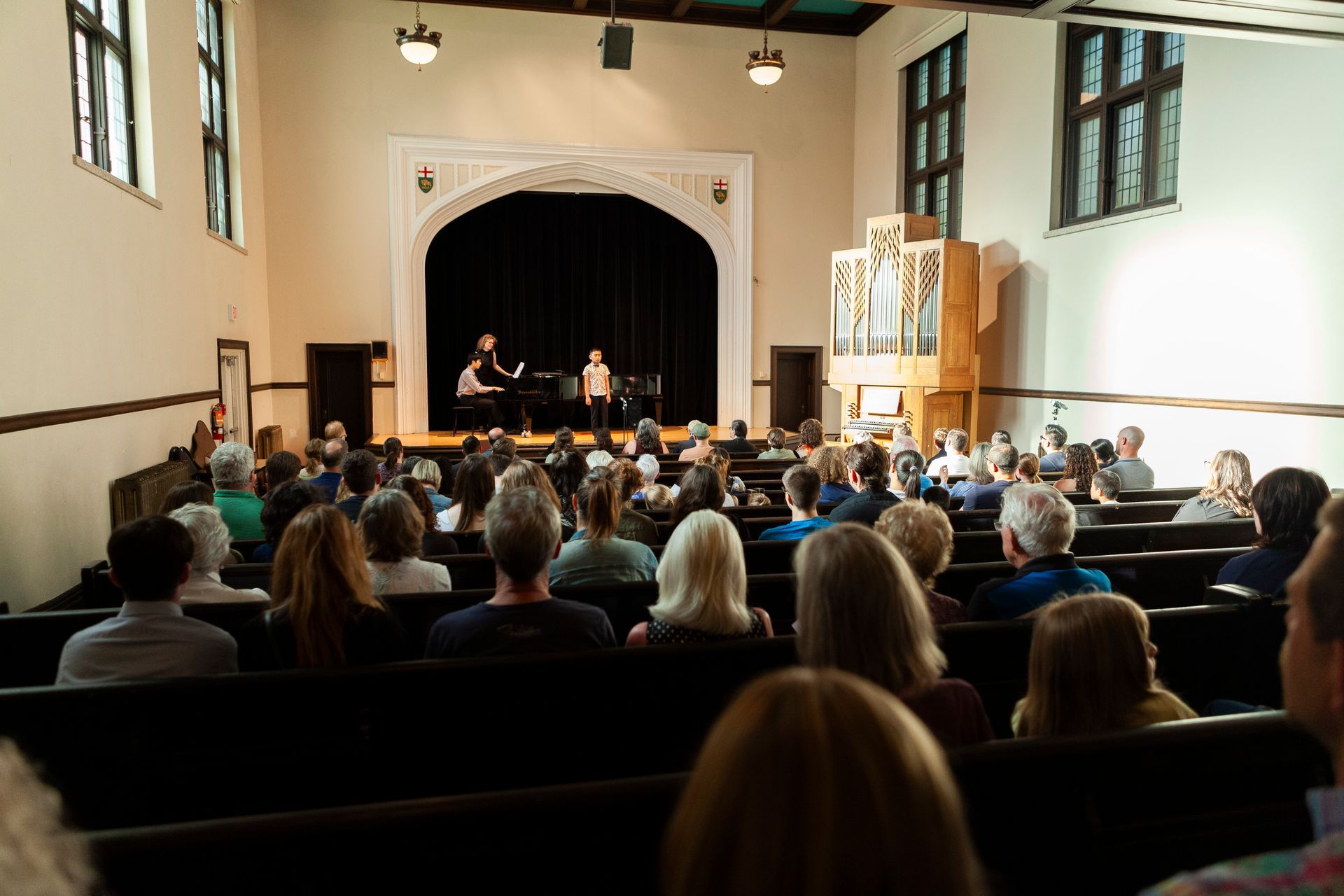 A large group of people are sitting in a church watching a concert