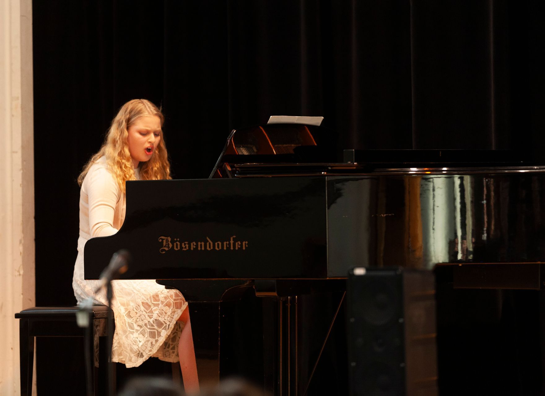 A woman is playing a piano on a stage.