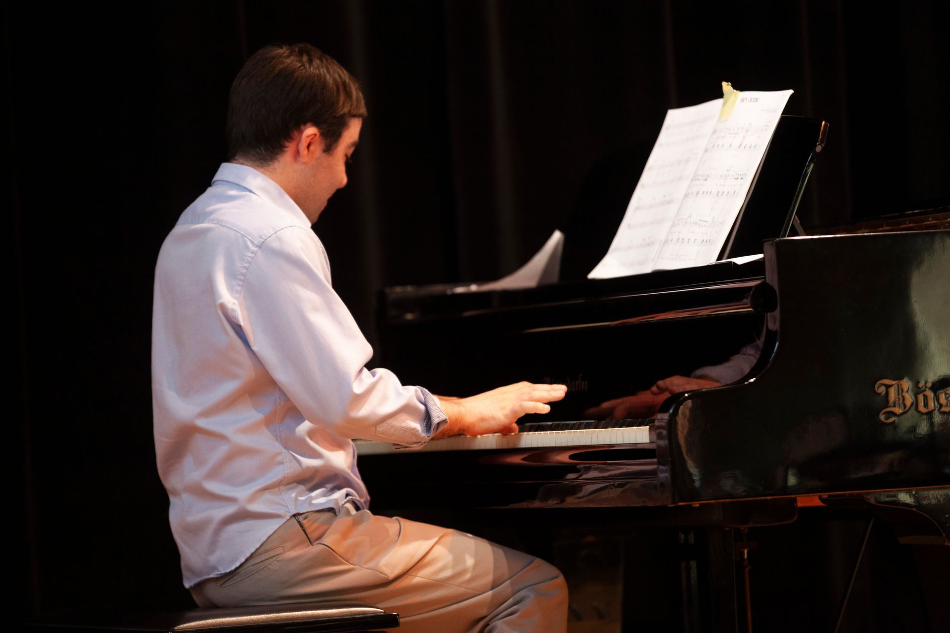 A man in a white shirt is playing a piano