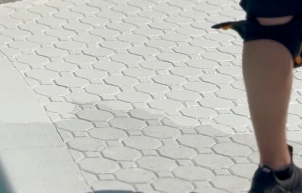 A person wearing knee pads is walking on a brick sidewalk.