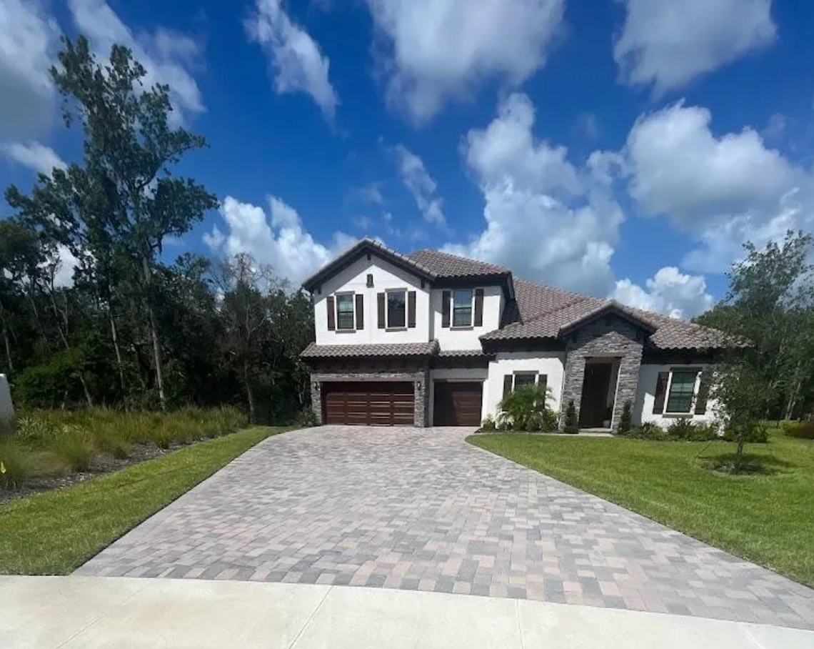 A large house with a brick driveway in front of it