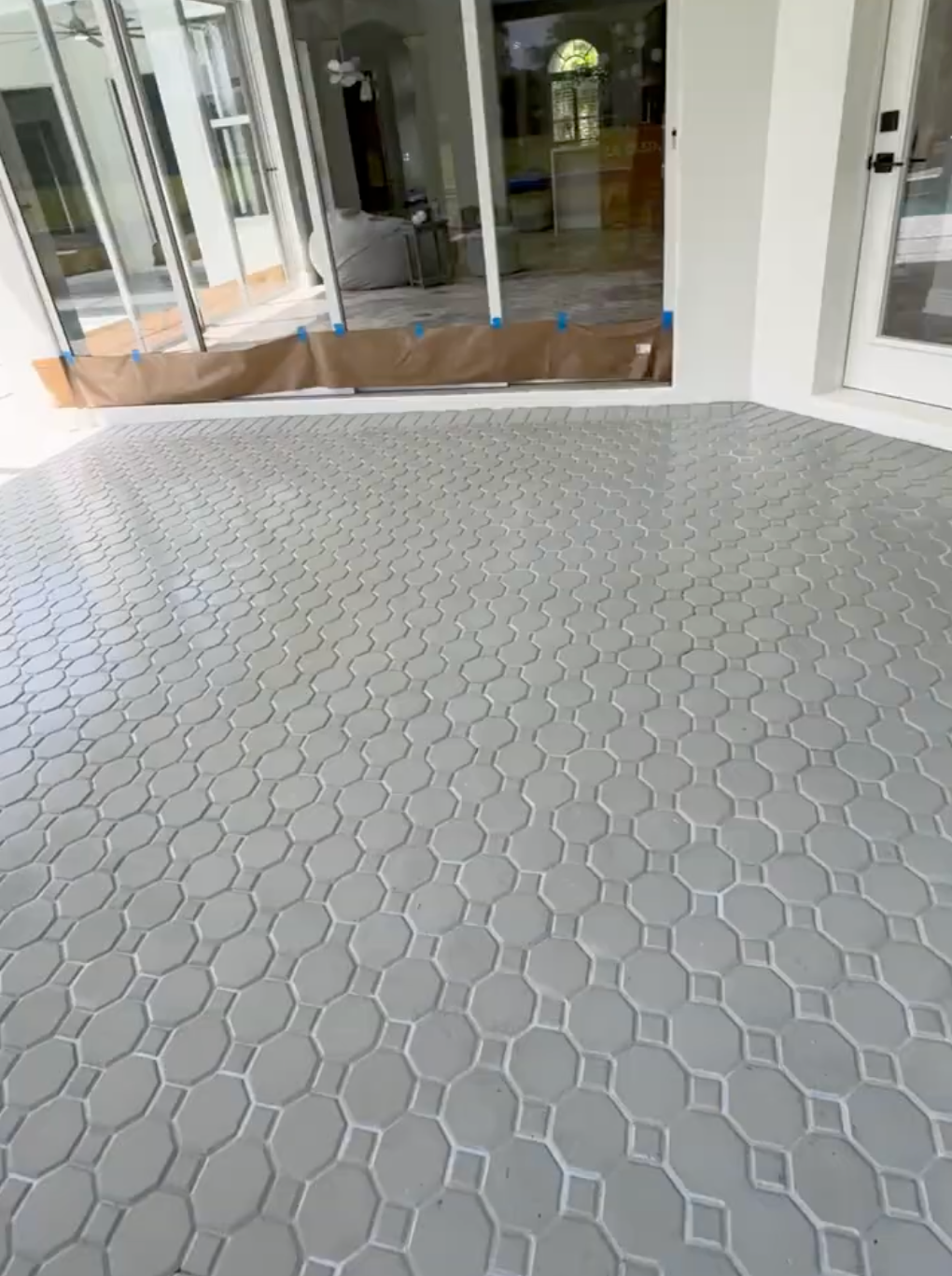 A gray tile floor in a room with a sliding glass door.