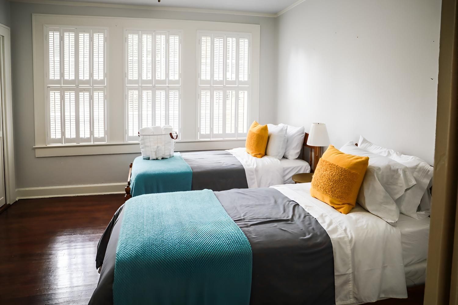 A Bedroom With Two Beds and a Window With Shutters — Manning Blinds & Awnings in Old Bar, NSW
