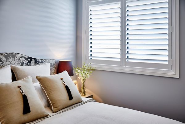 A Window With White Shutters and a Plant in Front of It — Manning Blinds & Awnings in Taree, NSW