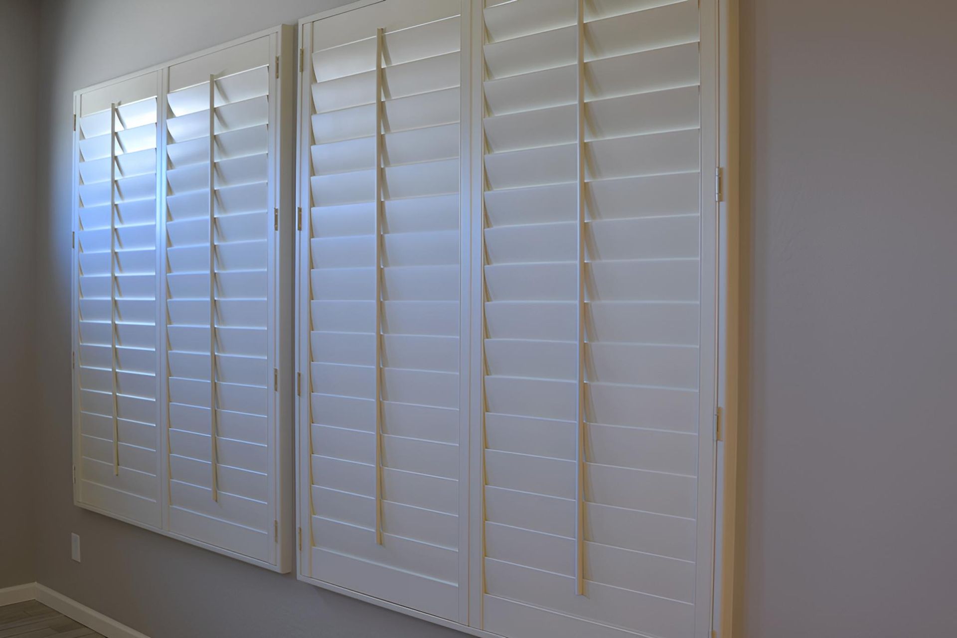 Three White Shutters Are Hanging on a Wall in a Room — Manning Blinds & Awnings in Forster, NSW