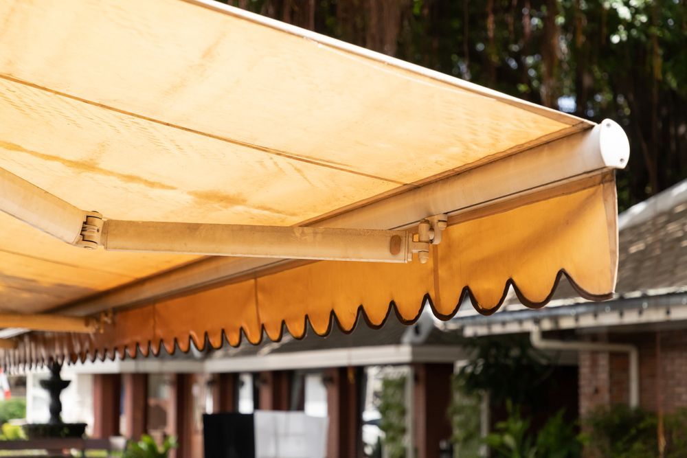 A Yellow Awning is Sitting on the Side of a Building — Manning Blinds & Awnings in Taree, NSW