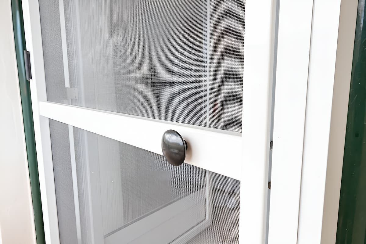 A Close Up of a White Screen Door With a Black Handle — Manning Blinds & Awnings in Taree, NSW