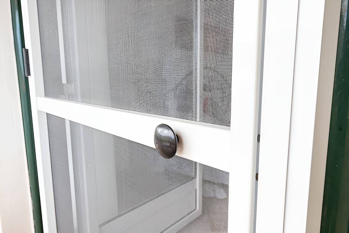 A Close Up of a White Screen Door With a Black Handle — Manning Blinds & Awnings in Forster, NSW
