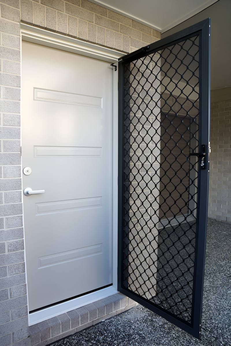 A White Door With a Black Screen on the Side of It — Manning Blinds & Awnings in Hallidays Point, NSW