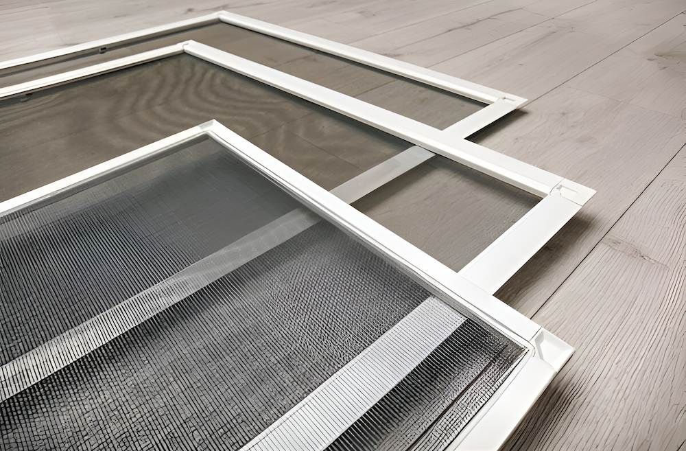 Three Mosquito Screens Are Stacked on Top of Each Other on a Wooden Floor — Manning Blinds & Awnings in Taree, NSW