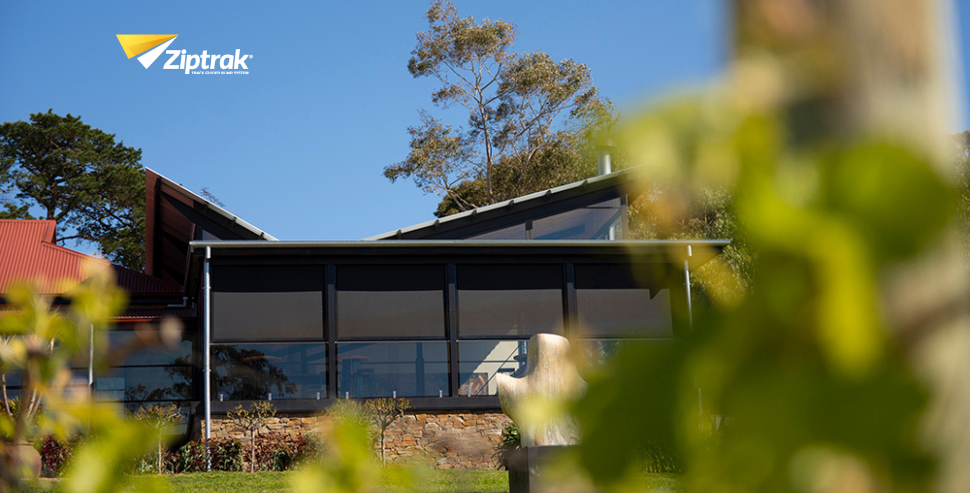 A building with black outdoor blinds in a vineyard under a clear blue sky — Manning Blinds & Awnings in Taree, NSW