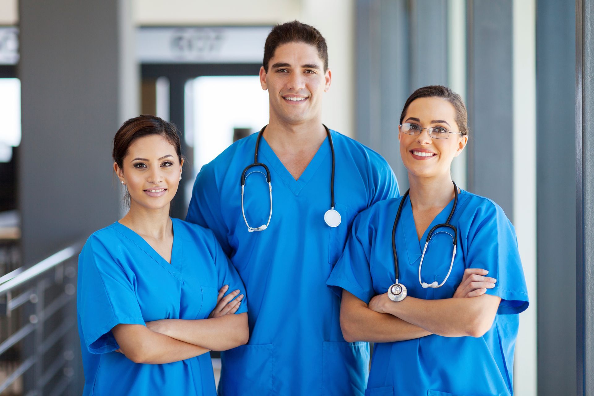 A group of doctors and nurses are posing for a picture in a hospital hallway.