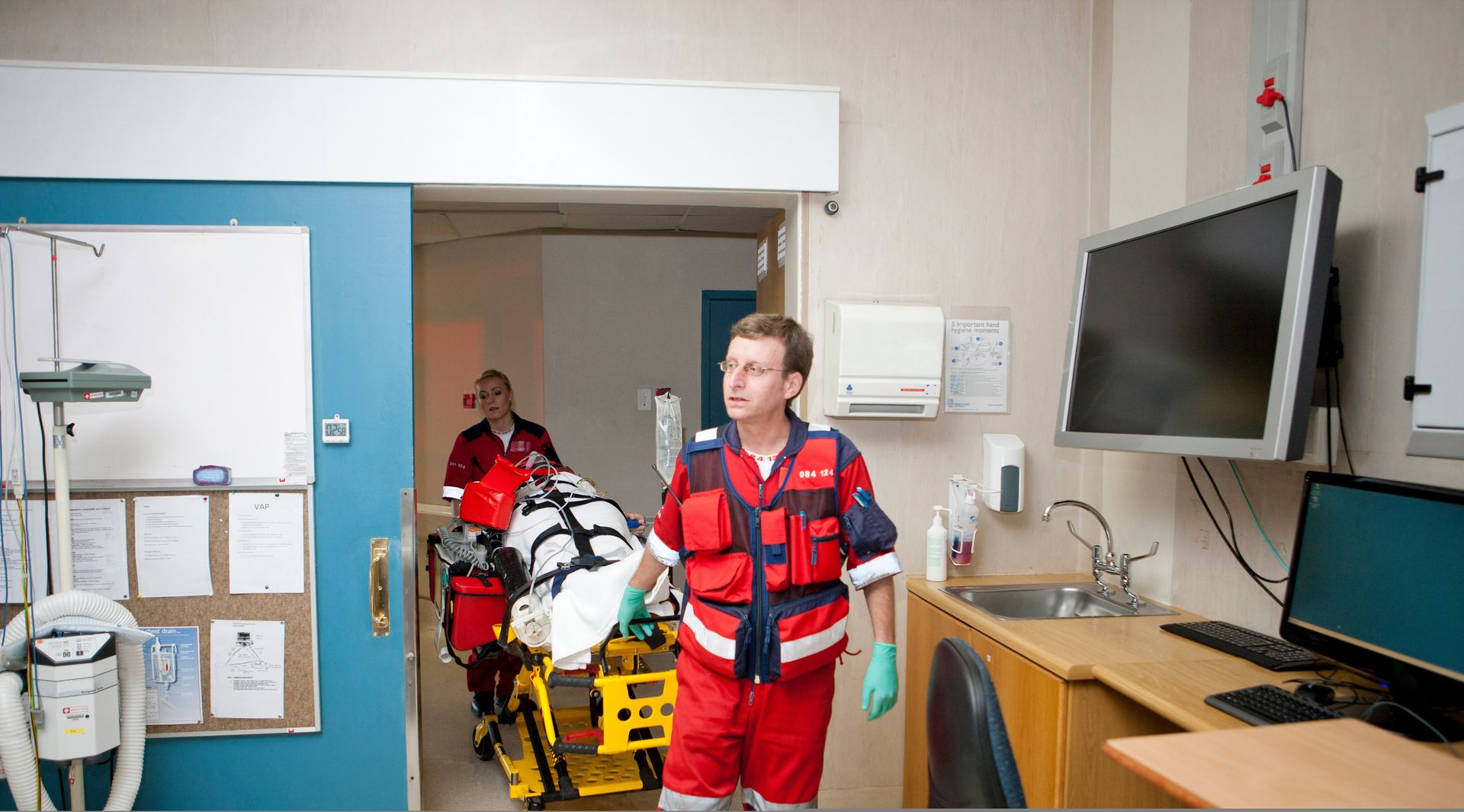 Male paramedic in uniform pushing patient on a corridor to emergency room.