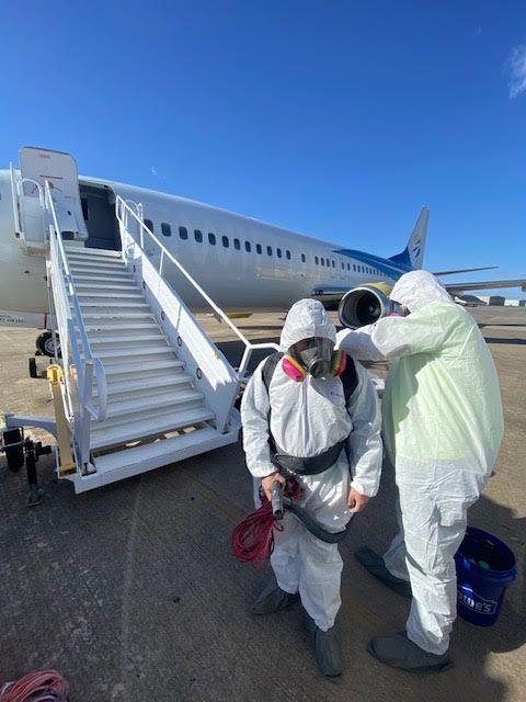 A man in a protective suit is getting ready to board an airplane