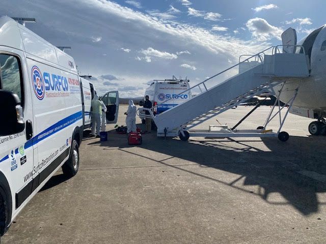 A white van is parked next to a plane on a runway.