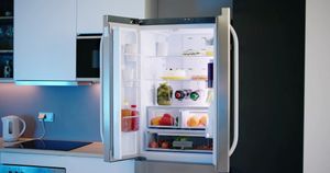 Open refrigerator in a modern kitchen with food, drinks, and a visible freezer compartment.