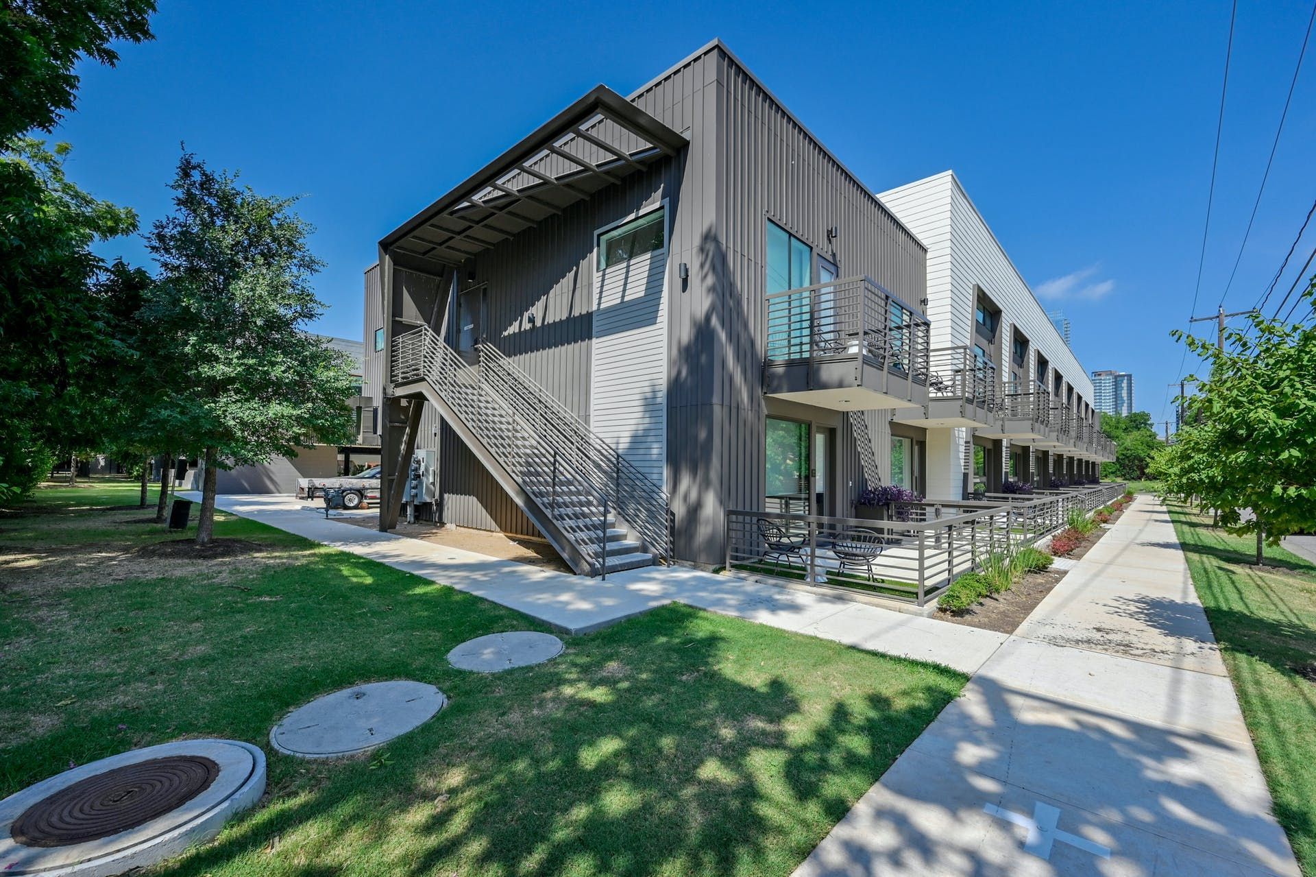 A large building with stairs leading up to it is surrounded by grass and trees.