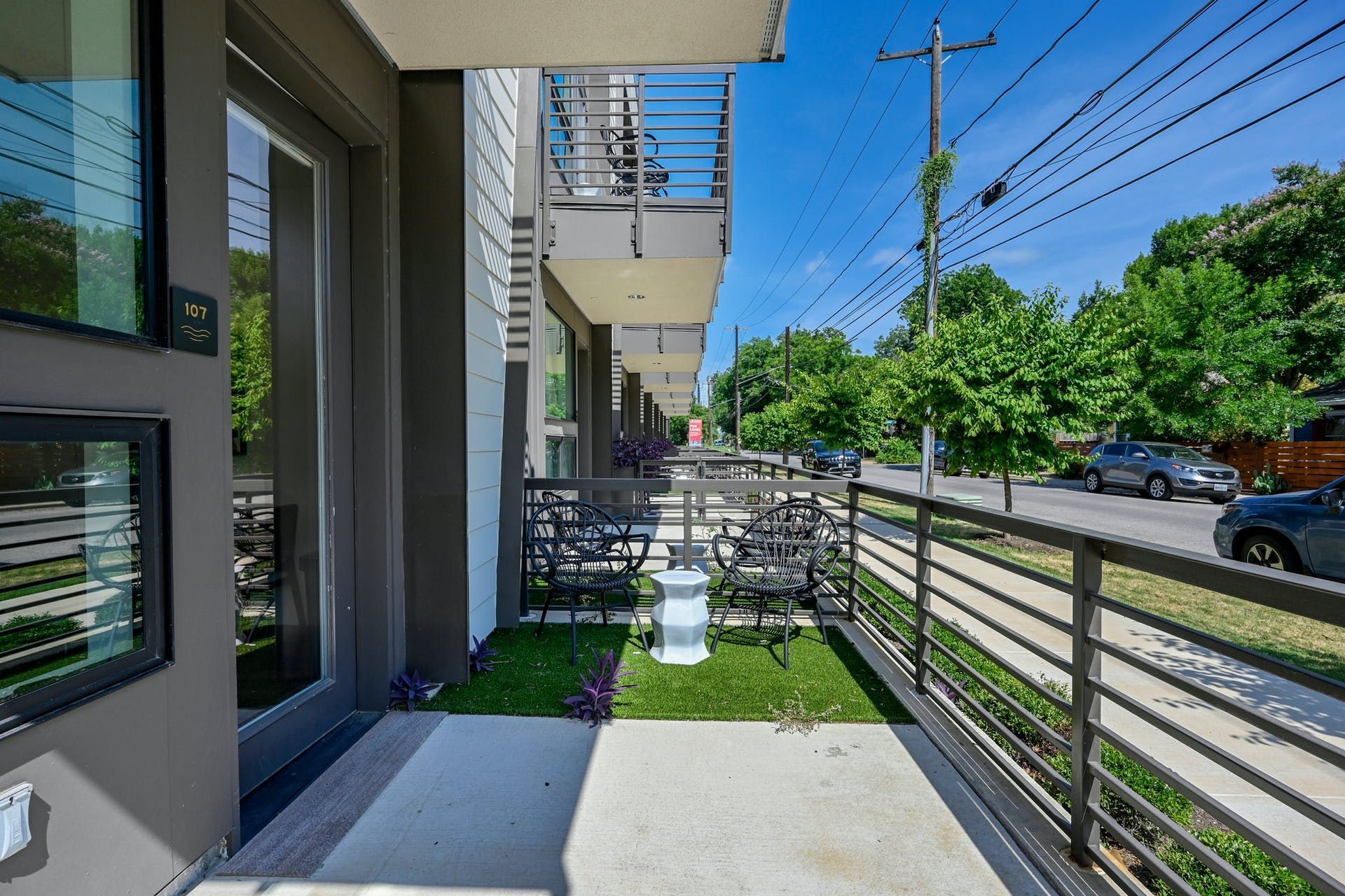 A balcony with a fence and a lawn in front of a building.