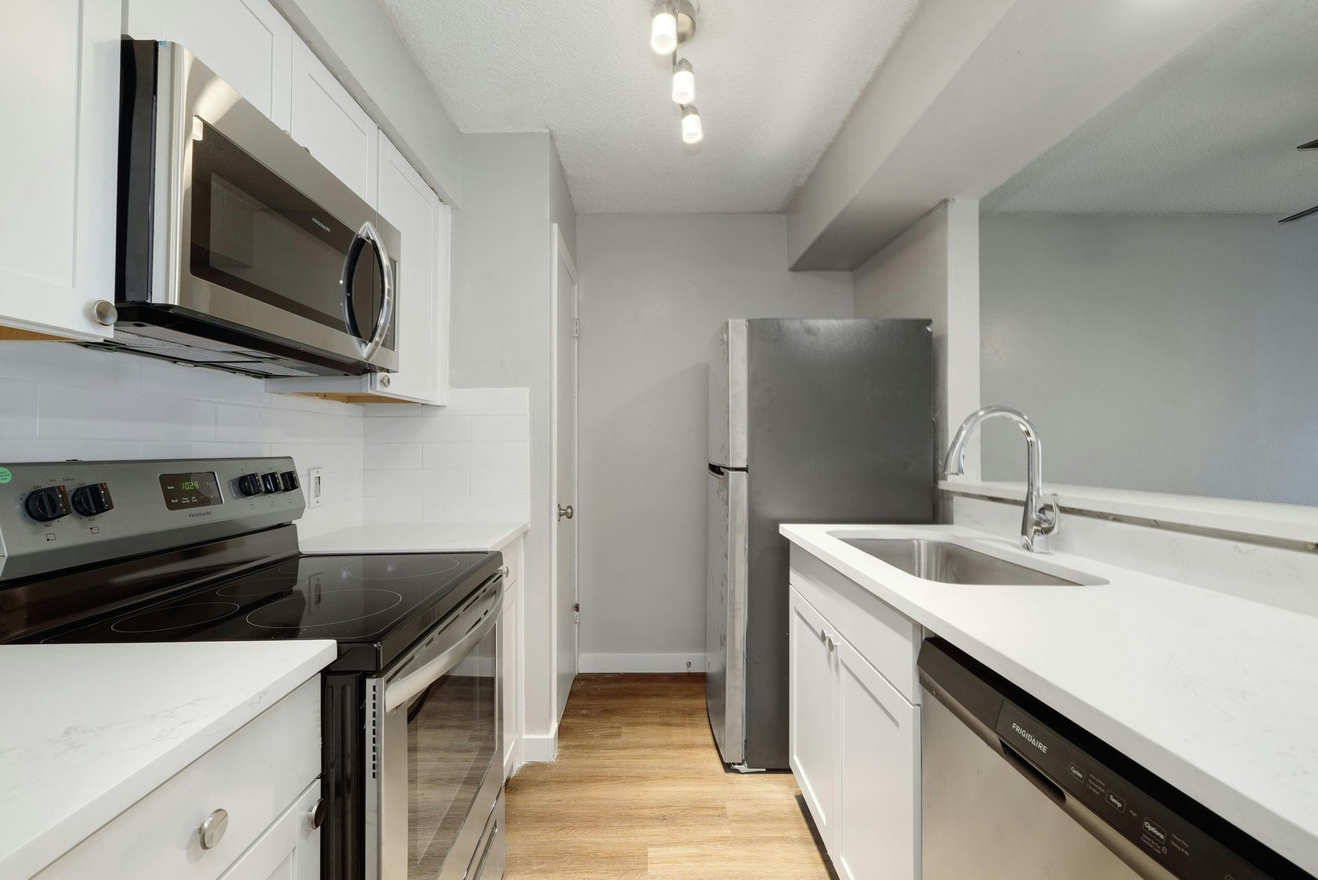 A kitchen with a stove , microwave , refrigerator , sink and dishwasher.