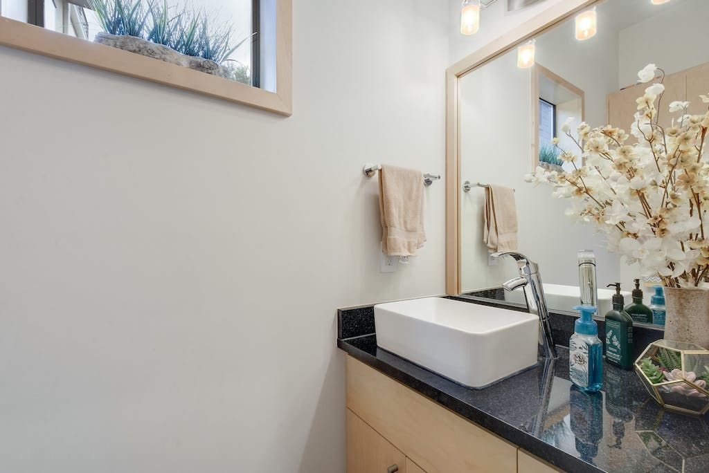 A bathroom with a sink , mirror and window.