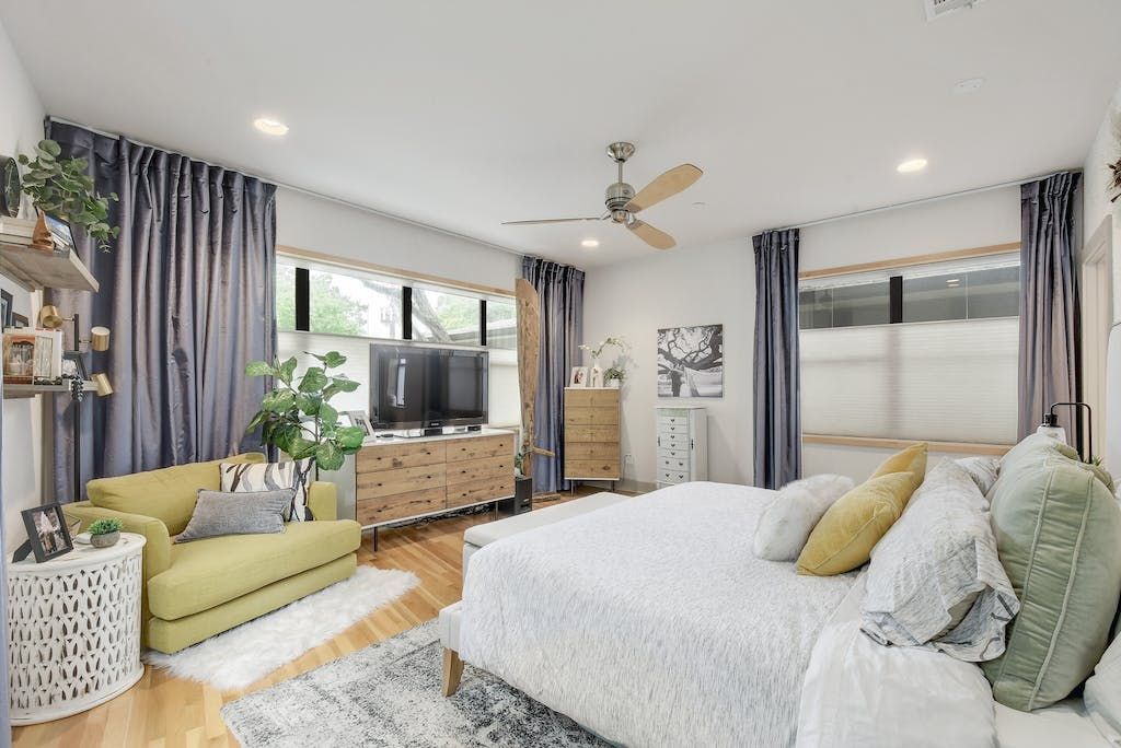 A bedroom with a bed , couch , television and ceiling fan.