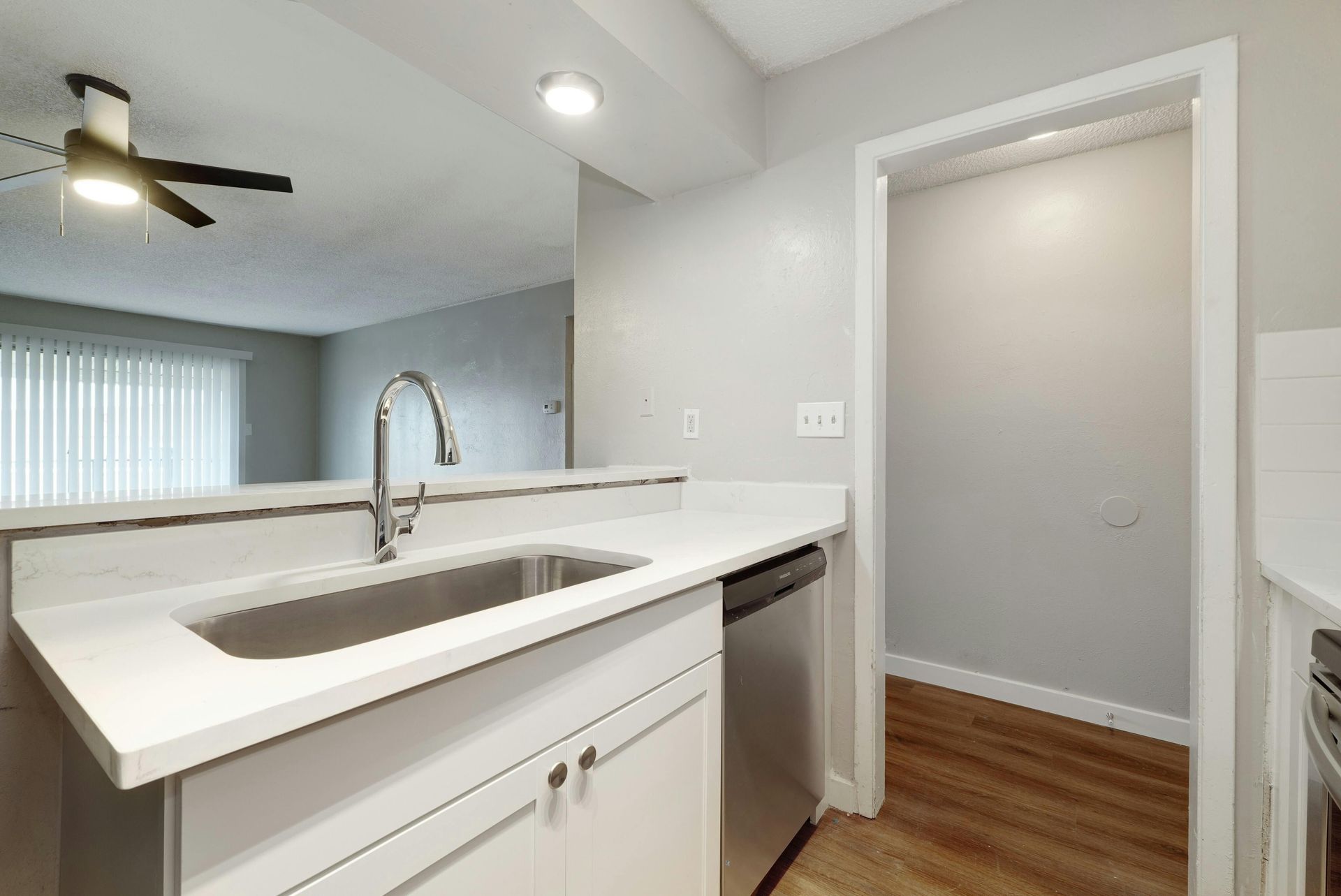 A kitchen with a sink , dishwasher , and ceiling fan.