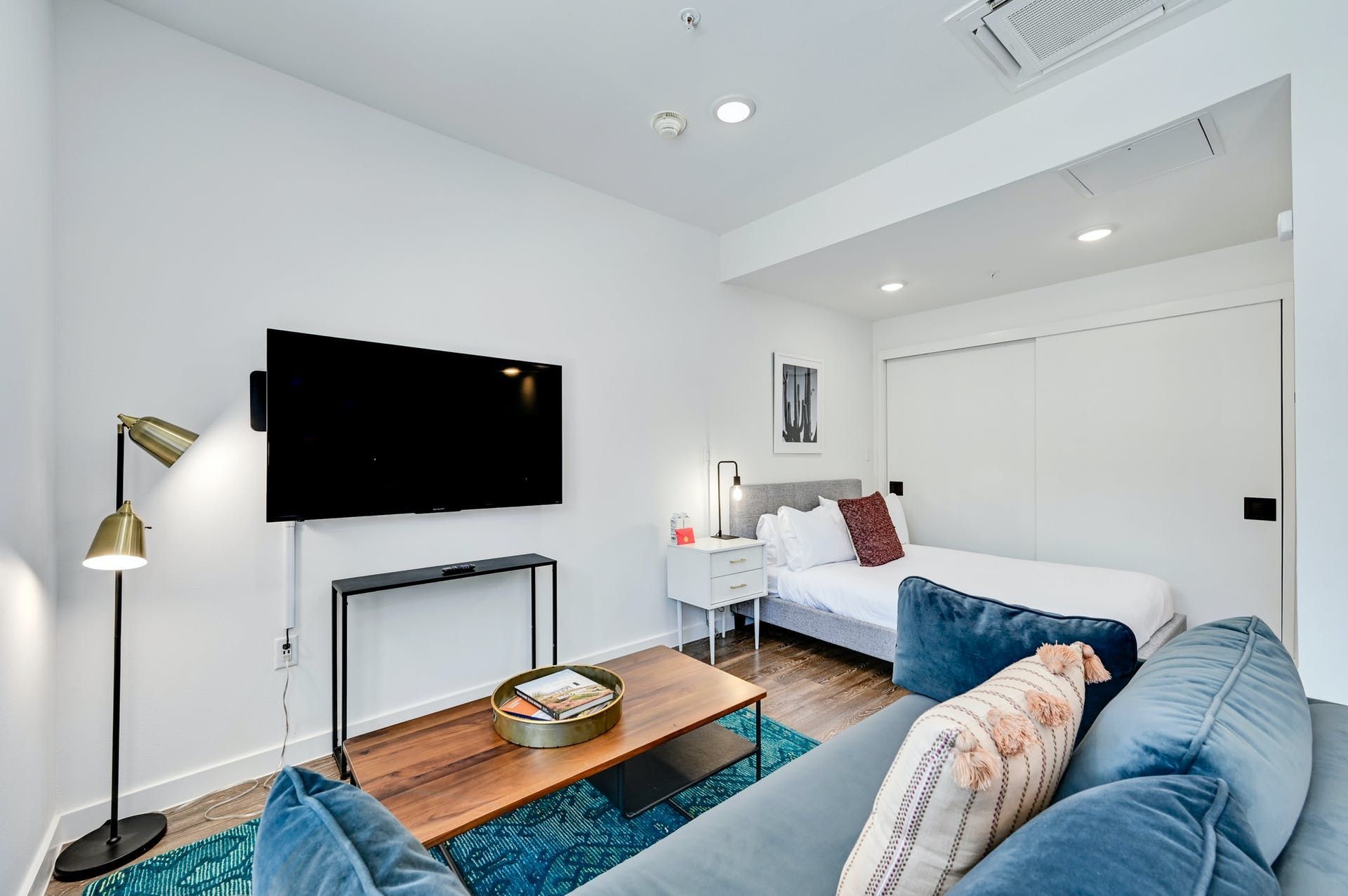 A living room with a couch , coffee table , television and bed.
