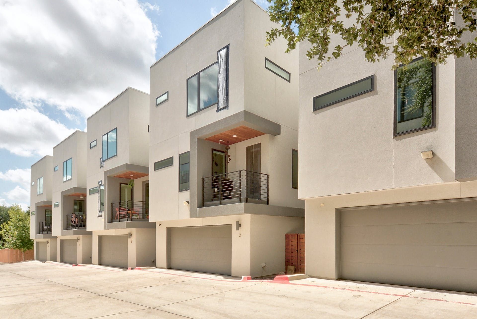 A row of white apartment buildings with garages and balconies