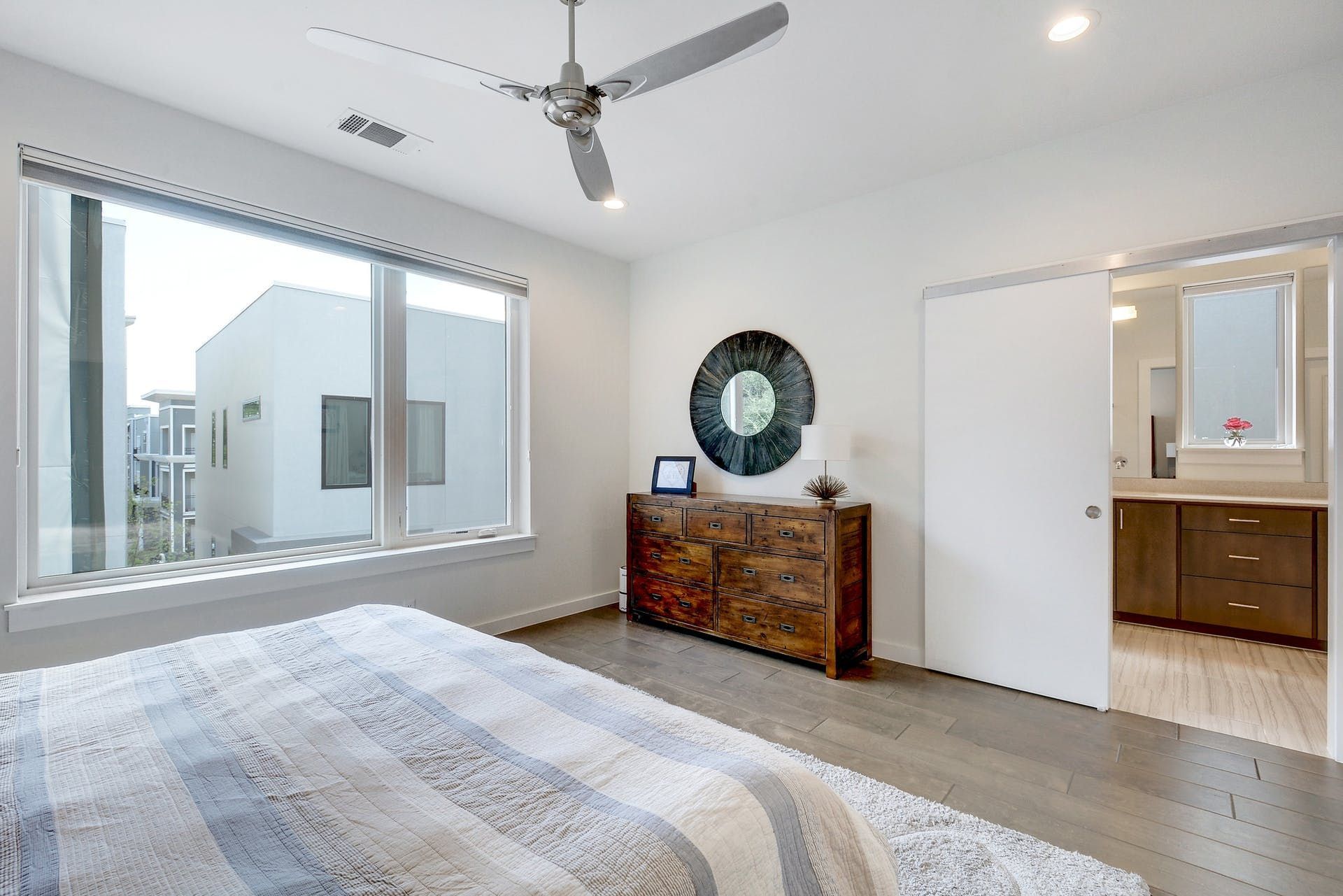 A bedroom with a bed , dresser , mirror and ceiling fan.