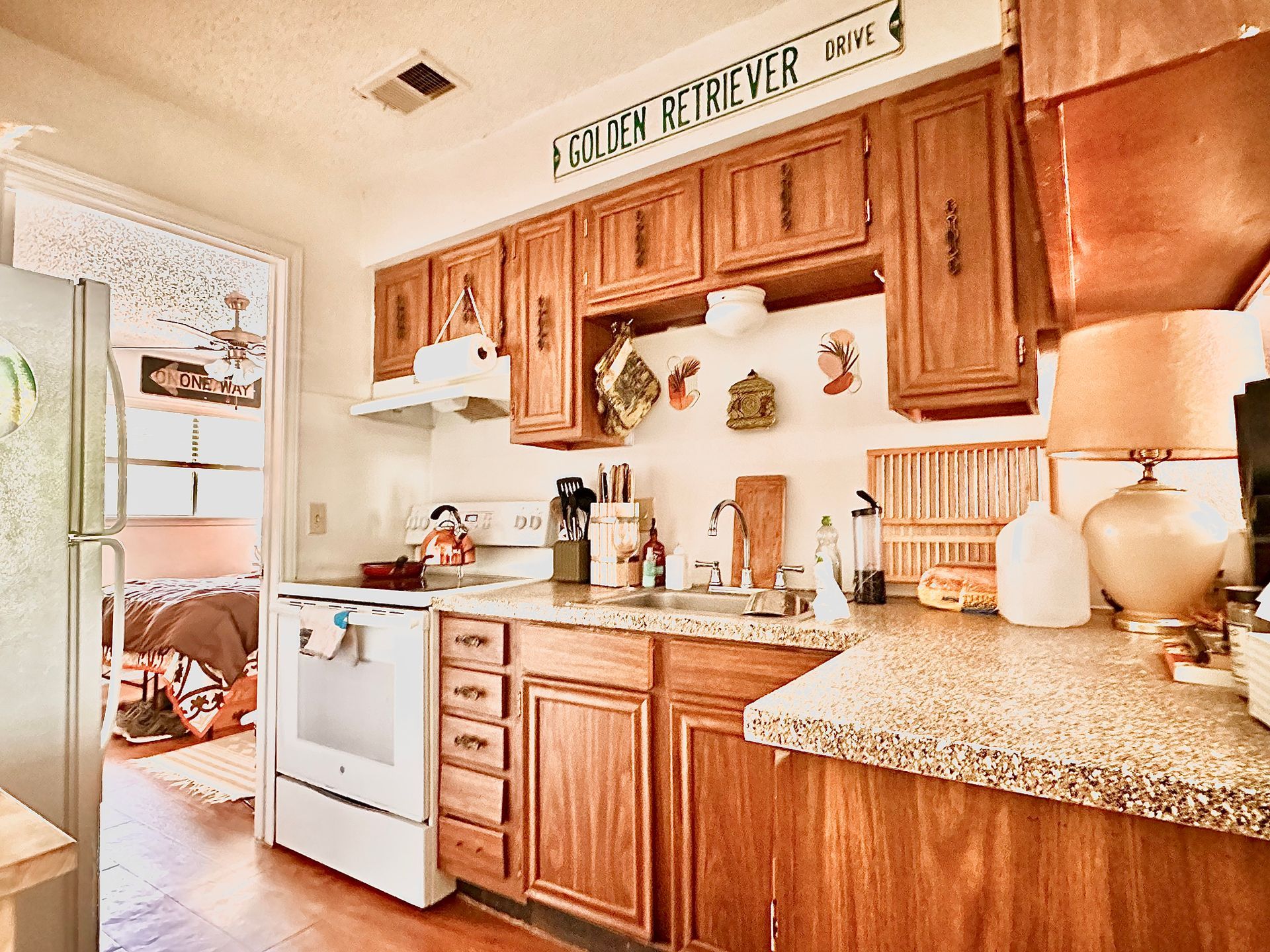 A kitchen with wooden cabinets , granite counter tops , a stove and a refrigerator.
