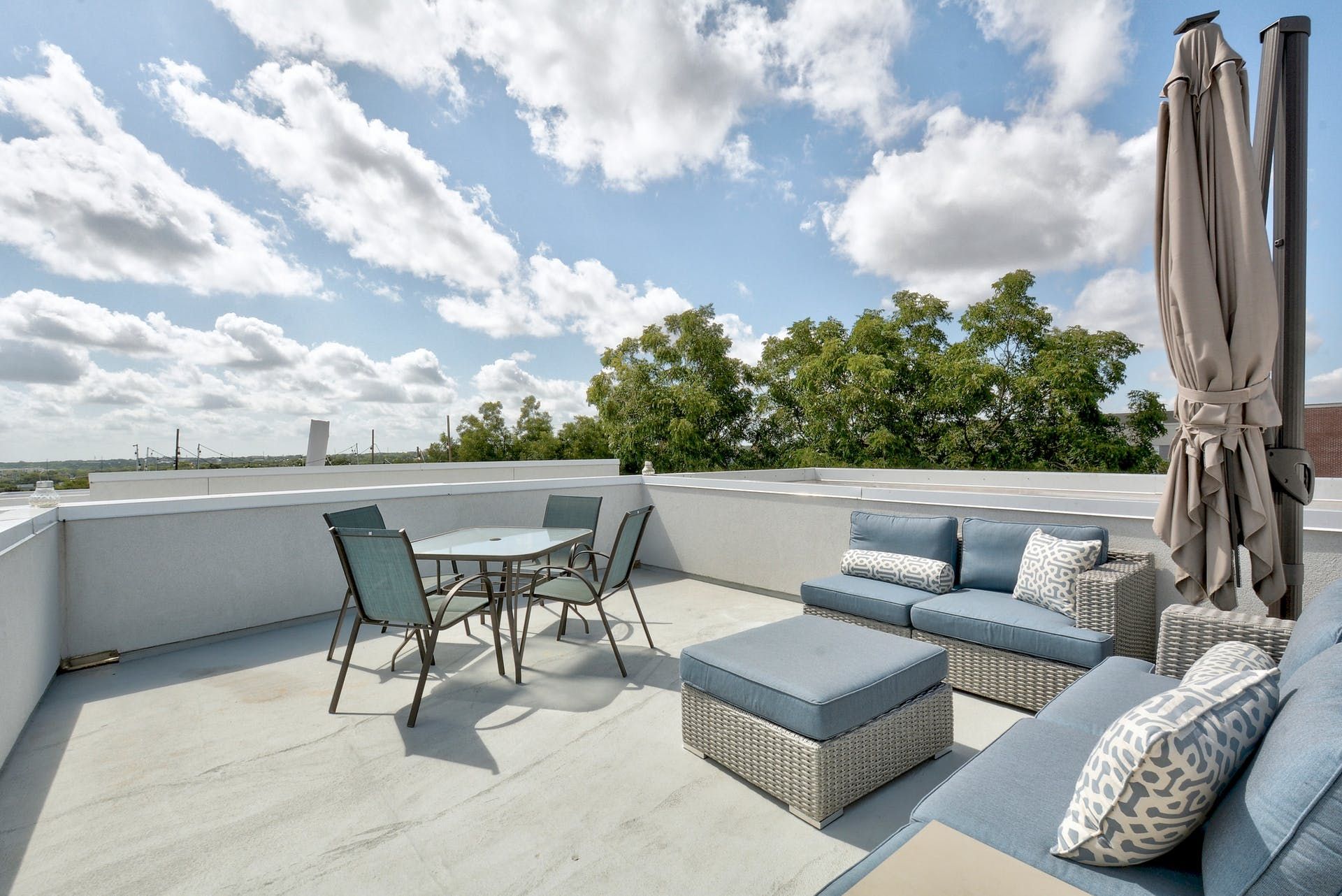 A rooftop deck with furniture and umbrellas on a sunny day