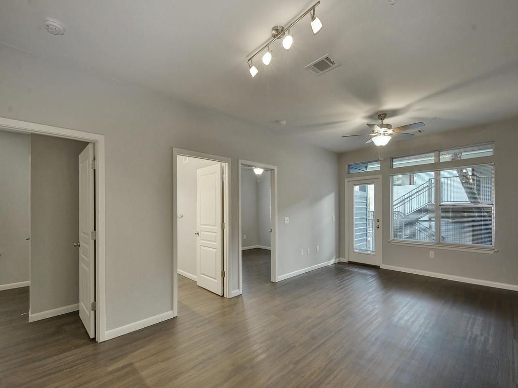An empty living room with hardwood floors and a ceiling fan.
