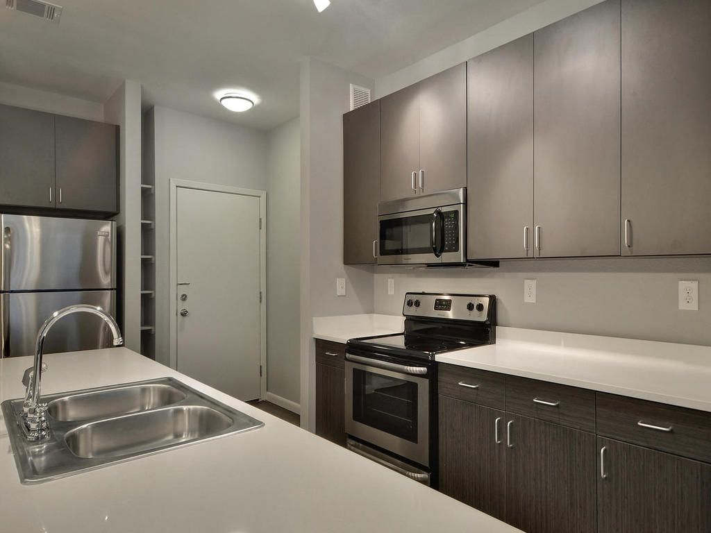 A kitchen with stainless steel appliances and gray cabinets
