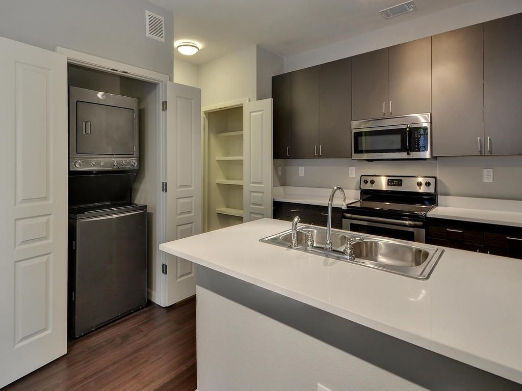 A kitchen with a washer and dryer and a sink