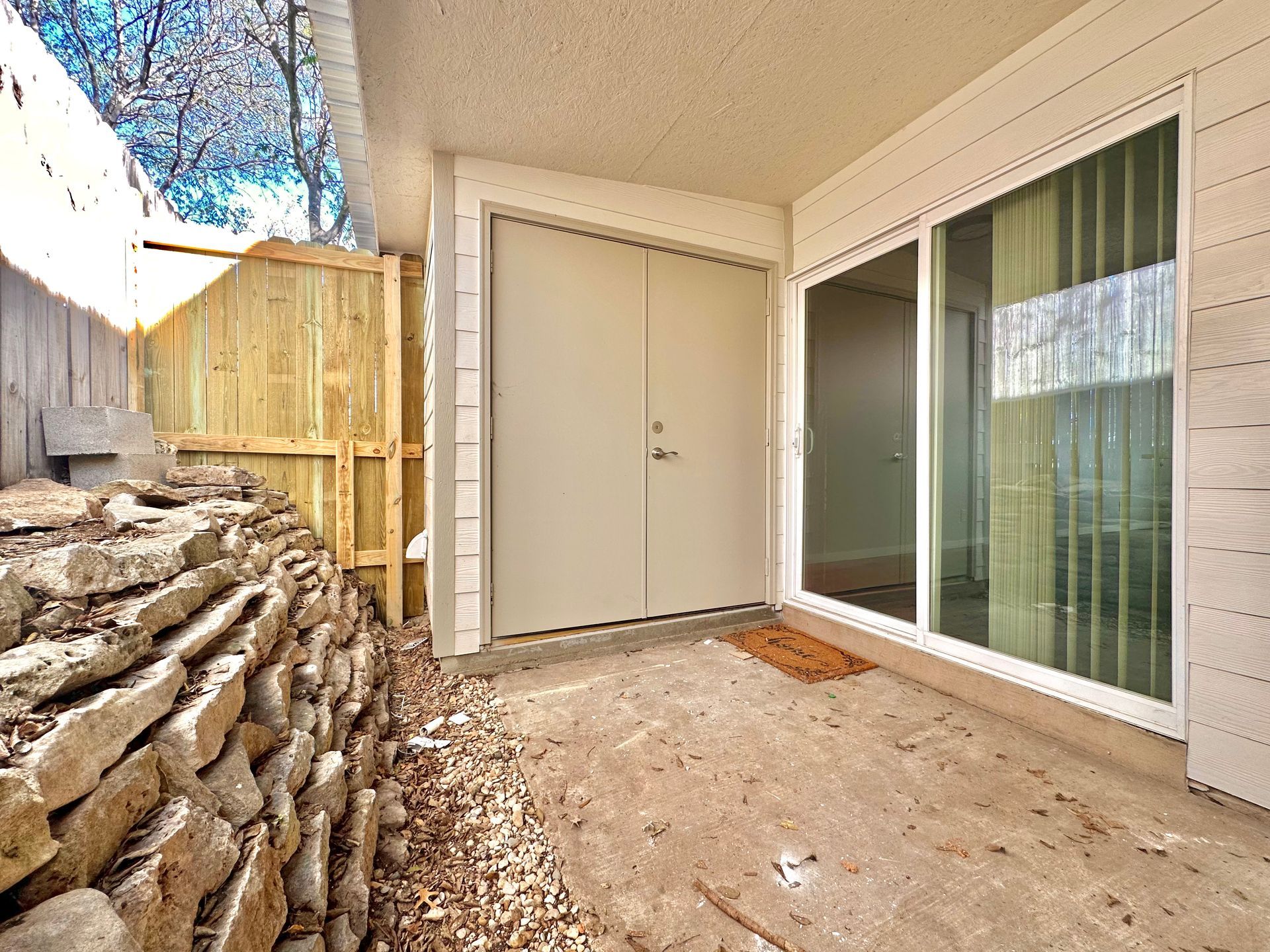 A patio with a sliding glass door and a stone wall.